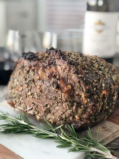 a meatloaf on a cutting board with rosemary sprigs next to it