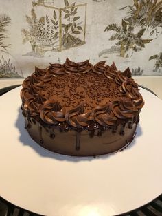 a large chocolate cake sitting on top of a white plate next to a wallpaper