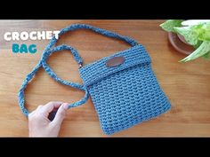 the crochet bag is being held by someone's hand on a wooden table