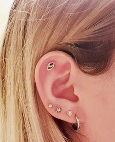 a close up of a person's ear with three different piercings on it