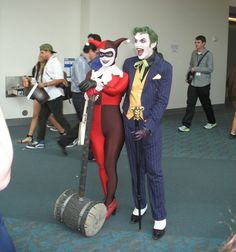 two people dressed up as the joker and catwoman in an office lobby with other people