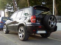 the back end of a black suv parked on the side of the road next to another car