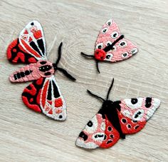 three embroidered butterflies sitting on top of a wooden table