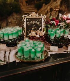 green candles are sitting on a table in front of a chalkboard