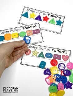 two hands are holding colorful buttons and matching them with name tags to spell out shapes