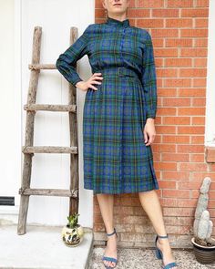 Vintage Talbots Petite Checkered Blue and Green Button Down Dress with Belt.  Polyester...the silky smooth kind. Elastic waist, fabric covered buttons. Belt loop. Shoulder pads. Metal snaps at the neck and waist. Buttons on the cuffs. Vintage Size 12. Model is 6'. Belt has wear on one of the holes, as pictured. L: 47.5" Underarm to underarm: 21" Waist: 14" stretches to 19" shoulder to shoulder: 16.5" shoulder to cuff: 23". Belt size: 12. Length of belt: 35.5". Check out the rest of our shop: https://instagram.com/hollyshopvintage?igshid=OGQ5ZDc2ODk2ZA== https://hollyshopvintage.etsy.com/ Orders over $35 ship for free. Please check out my Instagram for my newest finds: Hollyshopvintage  Everything priced over $35 has shipping already included in the total price. I'll gladly combine shipping Blue Belted Button-up Dress, Plaid Midi Dress With Buttons, Retro Blue Button-up Dress, Vintage Blue Button-up Dress, Blue Buttoned Midi Dress For Fall, Blue Fitted Shirt Dress With Button Closure, Fitted Blue Shirt Dress With Button Closure, Blue Mid-length Buttoned Dress, Fall Blue Midi Dress With Buttons