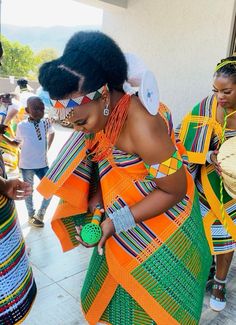 two women in colorful dresses standing next to each other and one woman is holding a drum