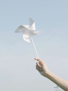 a hand holding a white pinwheel in the air