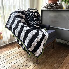 a black and white crocheted afghan sitting on top of a couch next to a tv