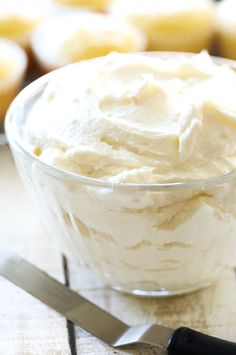 a glass bowl filled with whipped cream next to a knife