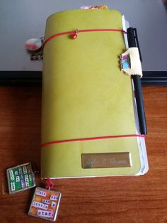 an open yellow notebook sitting on top of a wooden table next to two small magnets