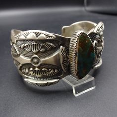 "VINTAGE MARC ANTIA BRACELET DESCRIPTION: This outstanding cuff is from celebrated Apache artisan, Marc Antia. Deep and intricate hand-stamped designs enhance the heavy gauge sterling silver cuff. The dark blue-green Pilot Mountain cab sits up high in picket fence bezel. This museum quality bracelet will be a cherished addition to your collection of fine vintage Native American jewelry. MEASUREMENTS: Interior of the cuff measures 6\" with an additional 1 1/8\" non-adjustable gap. Total circumfer Unique Collectible Cuff Bracelet, Vintage Patina Cuff Bracelet, Vintage Cuff Bracelet With Patina, Handmade Antique Cuff Bracelet, Handmade Vintage Cuff Bangle, Antique Handmade Cuff Bracelet, Traditional Patina Cuff Bracelet As Gift, Handmade Antique Cuff Bracelets, Traditional Cuff Bracelet With Patina As Gift