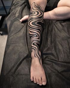 a woman laying on top of a bed with her legs covered in black and white tattoos