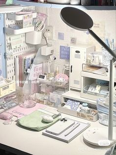 a desk with many items on it and a lamp in the corner next to it