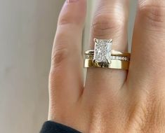 a woman's hand with a diamond ring on top of her finger and the other hand holding it