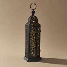 an ornate black lantern with gold stars on the top and bottom, sitting on a beige background