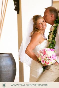 a bride and groom standing together in front of a vase