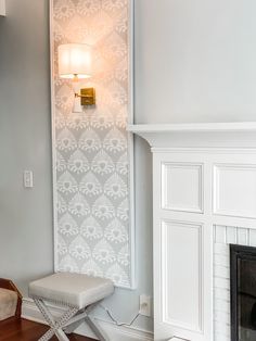 a living room with a fireplace and white wallpaper on the walls, along with a bench