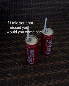 two coke cans with straws in them sitting on the ground