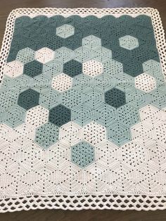 a crocheted tablecloth with hexagons on it, sitting on a wooden floor