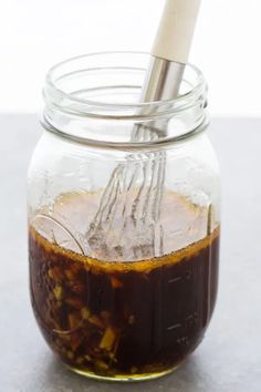 a glass jar filled with liquid and a whisk