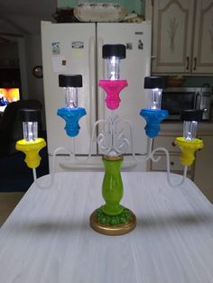 a green candle holder sitting on top of a white table next to a refrigerator freezer