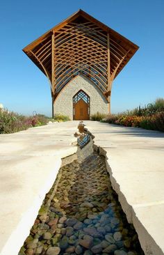 a building with a water feature in front of it and flowers growing around the entrance