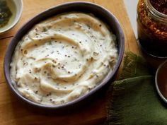 there is a bowl of hummus next to two bowls of sauces on the table