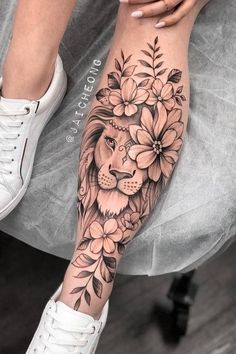 a woman's leg with flowers and a lion on it