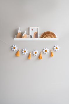 a white shelf with flowers and decorations on it, hanging from the wall next to a plate