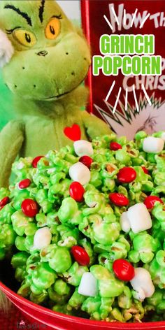 the grinch popcorn is green with red and white candies in it next to a stuffed animal