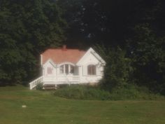 a white house sitting in the middle of a lush green field