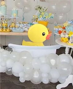 a rubber ducky bathtub filled with white balloons for a baby's shower