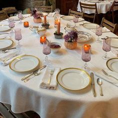 the table is set with plates, silverware and candles