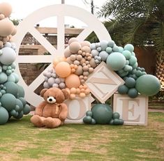 there is a teddy bear sitting in front of balloons on the sign that says love