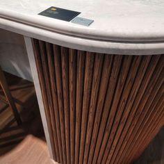 a close up of a table with a white marble top and brown wood slats