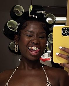 a woman holding up a cell phone with hair rollers on her head