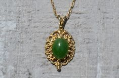 Ladies Vintage Yellow Gold Necklace set with Jade. Beautifully crafted in 14 karat yellow gold is an ornately designed oval pendant set in the center with a cabochon jade. The pendant measures just over 0.75 inch in length and dangles from an 18 inch yellow gold chain. The chain is complete with a spring ring style clasp. Another length chain (shorter or longer) can be swapped for this one for an additional charge. Each piece has been hand selected and meticulously identified and graded by a Gra Hallmarked Oval Jade Necklaces, Oval Jade Necklaces With Hallmark, Oval Jade Cabochon Necklaces, Oval Jade Cabochon Necklace, Elegant Jade Cabochon Necklace, Elegant Oval Cabochon Jade Jewelry, Elegant Engraved Jade Necklace, Oval Jade Gold Necklace, Vintage Oval Jade Necklace