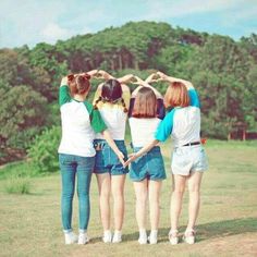 four girls are standing in a circle with their hands on their hipss and looking at the sky