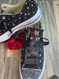 two pairs of black and white sneakers with hearts on them, one has a red rose