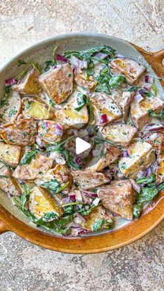 a skillet filled with potatoes and greens on top of a counter next to a wooden spoon