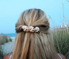 the back of a woman's head with two seashells in her hair