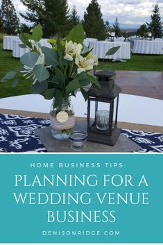 a vase filled with flowers sitting on top of a table next to a lantern and some tables