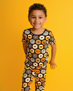 Popoki Halloween is here! Two piece short sleeve shirt with pants pajama set. Our exclusive hand drawn print features a black background with spooky fun Halloween themed donuts of Jack-o-lantern, black cat, mummy, spiderwebs, sprinkles and stripes. Earth-friendly, hypoallergenic bamboo viscose extra gentle on sensitive and eczema-prone skin. Breathable bamboo fabric adjusts to keep children snuggly and warm in winter, and cool and comfortable in summer. No snaps, buttons, or interior tags to rub Casual Black Sleepwear With Cartoon Print, Black Short Sleeve Sleepwear With Graphic Print, Black Graphic Print Short Sleeve Sleepwear, Playful Halloween Sleepwear, Fun Cartoon Print Short Sleeve Sleepwear, Black Cartoon Print Sleepwear For Sleepover, Black Cartoon Print Sleepwear For Pajama Party, Black Graphic Print Sleepwear For Bedtime, Black Cartoon Print Sleepwear