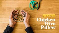 a person is holding a chicken wire pillow on a wooden table with scissors and pliers