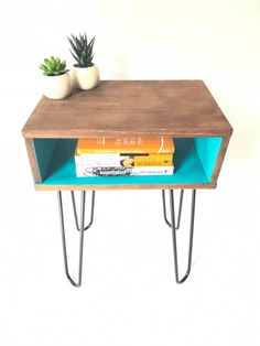 a table with some books on it and a plant in the corner next to it