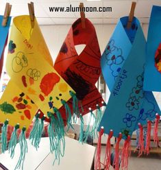 several colorful kites hanging from clothes pins