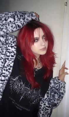 a woman with red hair wearing a black shirt and white leopard print jacket is posing for the camera