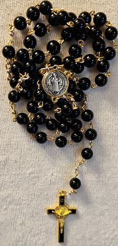 Handmade rosary Shiney Black beads with Saint Benidict crucifix and center With gold accents Cheap Handmade Black Rosary, Gold Beaded Crucifix Rosary, Rosary Necklace Black Gold, Black Hand-strung Rosary Bracelet With Round Beads, Black Beaded Cross-shaped Rosary, Saint Benedict, Prayer Beads, Handmade Beads, Gold Accents