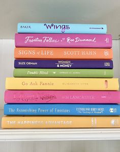 a stack of books sitting on top of a white shelf